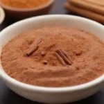 Un tazón de platos veganos vibrantes adornados con palos de canela y canela en polvo.