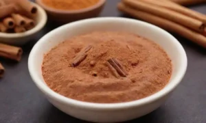 Un tazón de platos veganos vibrantes adornados con palos de canela y canela en polvo.