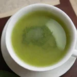 Una taza de té verde rodeada de hojas y un mapa mundial.