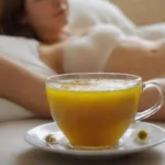 Taza de té de manzanilla junto a una persona que descansa mirando relajada.