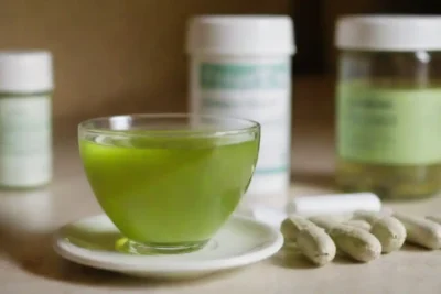 Una taza de té verde junto con varios medicamentos recetados.