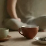 Un chorro de salvia junto a un té calmante y una persona relajada meditando.