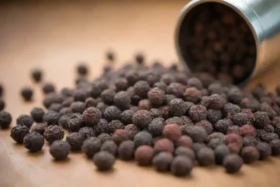 Cierre de palomitas de pimienta negras diseminadas sobre una superficie de madera con una antigua especia molienda.