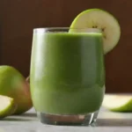 Un refrescante batido verde con rodajas de pera y frutas vibrantes en un vaso.