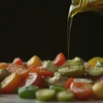 El aceite de oliva se derrama sobre verduras y hierbas mediterráneas frescas.
