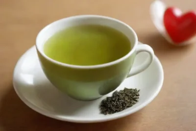 Una taza de té verde con una bolsa de té y iconos relacionados con la salud