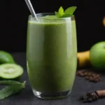 Un batido desintoxicante verde vibrante en un vaso rodeado de pimienta negra y ingredientes frescos.