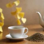 Hojas de ginkgo seco y semillas dispuestas junto a una taza de té de ginkgo.