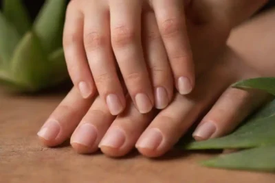 Aloe vera sale junto a uñas sanas en una superficie de madera.