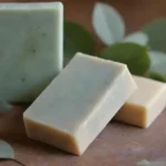 Hojas de eucalipto frescas junto a jabones artesanales en una mesa rústica.