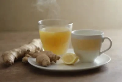 Fresco raíz de jengibre junto a una taza de té de jengibre y visuales relacionadas con la salud.