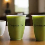 Dos tazas de té verde etiquetado orgánico y convencional lado a lado en una mesa.